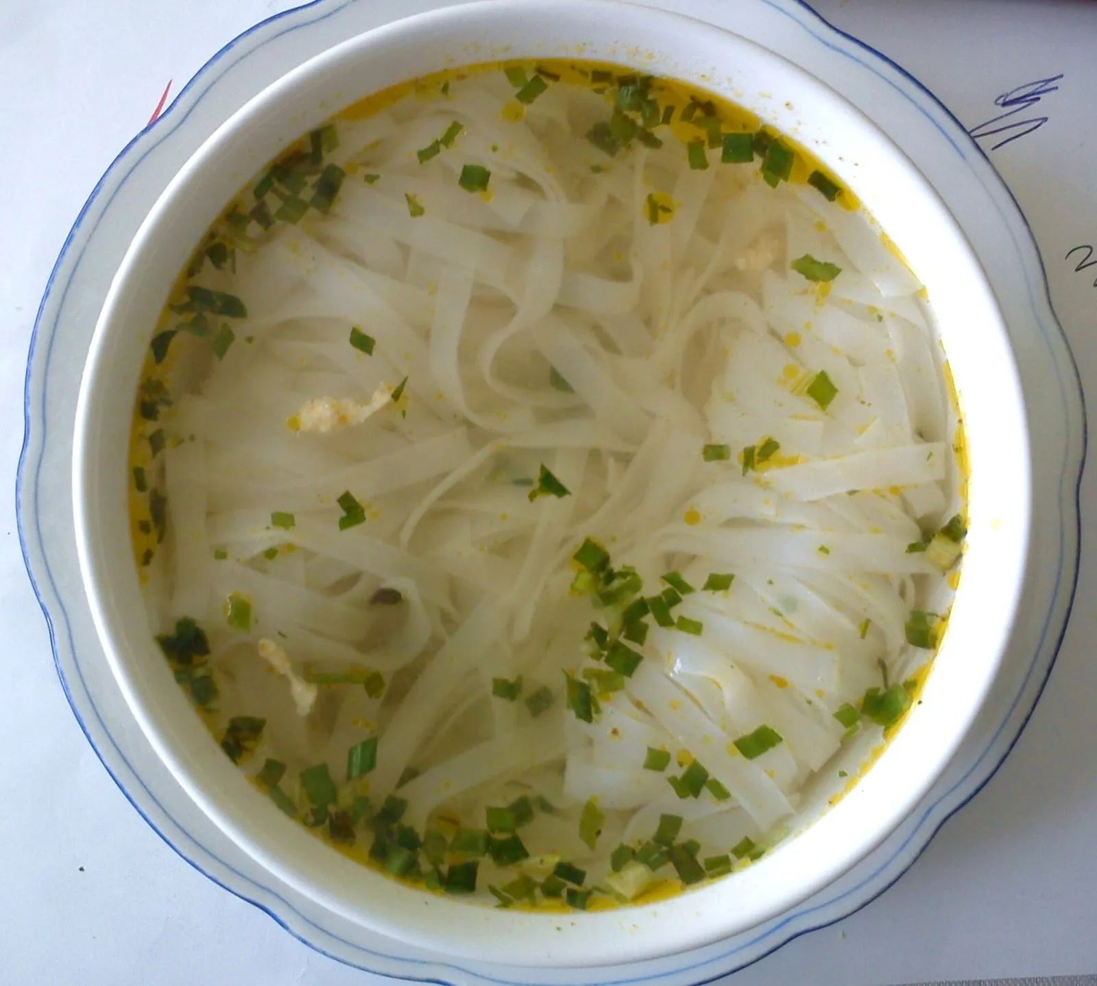 Klare Phở-Brühe mit breiten Reisnudeln und Frühlingszwiebeln