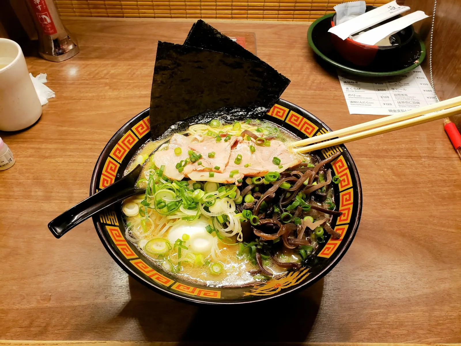 Schüssel vietnamesischer Nudelsuppe mit Kräutern und Beilagen