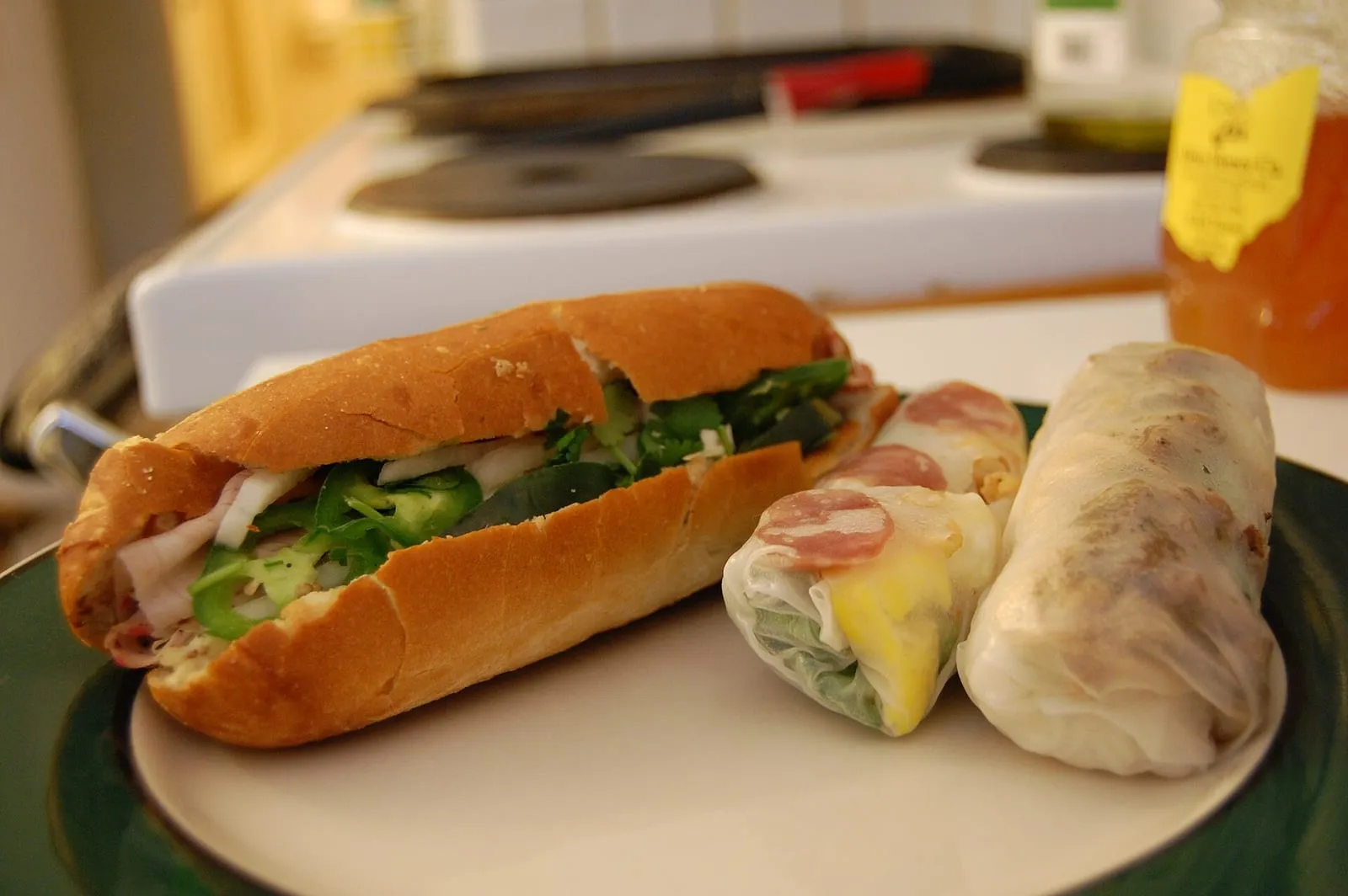 Bánh mì mit Aufschnitt und Kräutern, daneben frische Reisrollen
