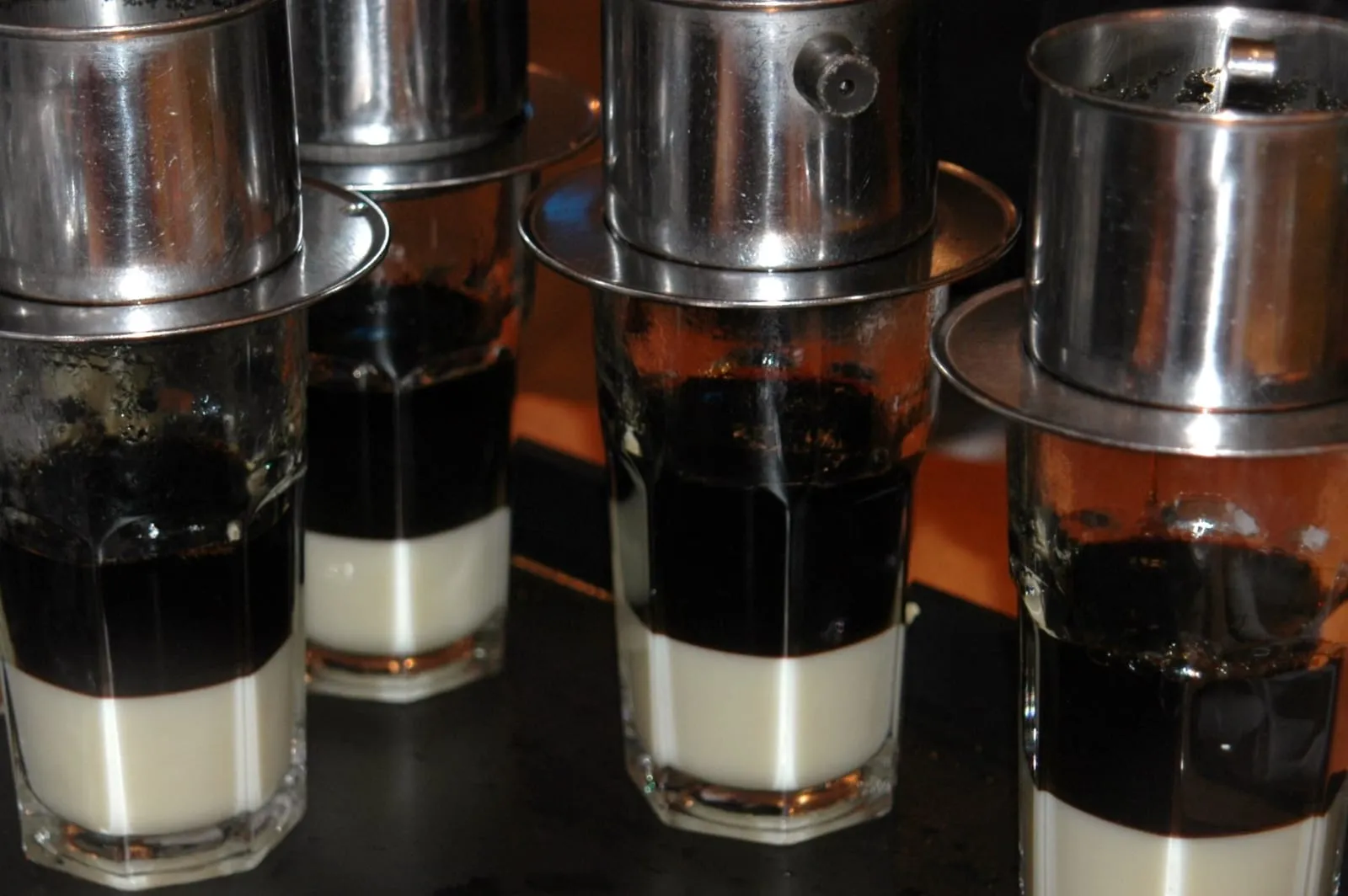 Vietnamesischer Kaffee tropft durch Phin-Filter auf gezuckerte Kondensmilch